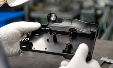 echnician inspecting an injection-molded plastic part for molding quality